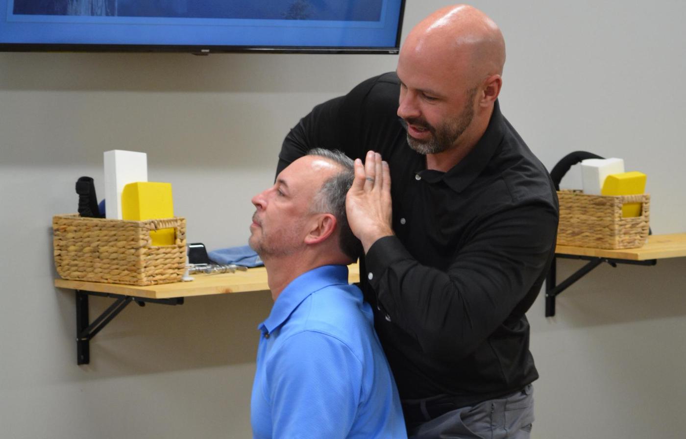 Dr. Coty Spraggs treating a man's headache pain  with a chiropractic adjustment