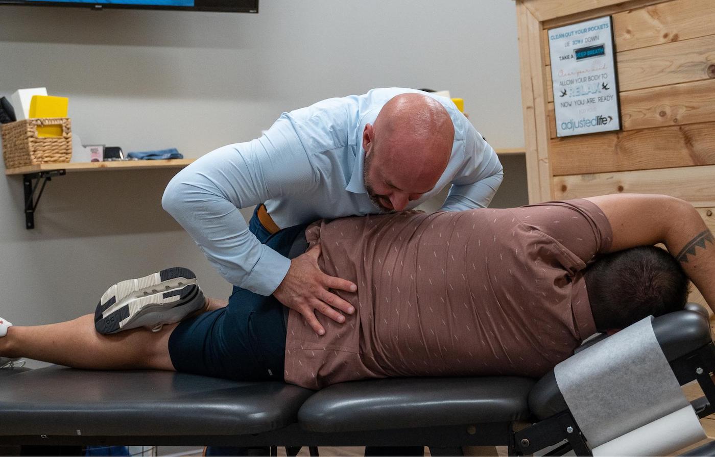 Dr. Coty Spraggs treating a man's hip pain with a chiropractic adjustment