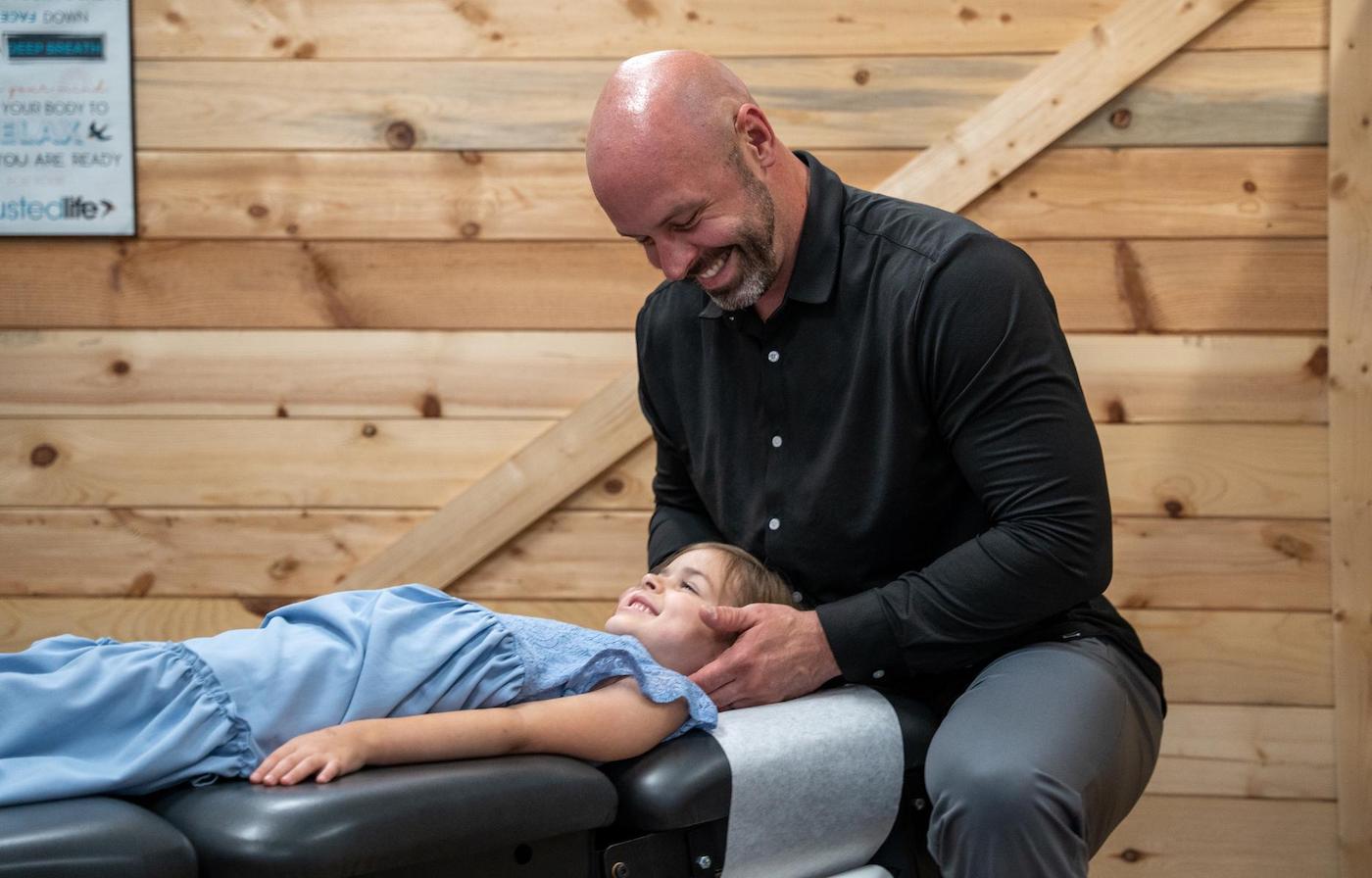 Dr. Coty Spraggs treating a young girl with a chiropractic adjustment