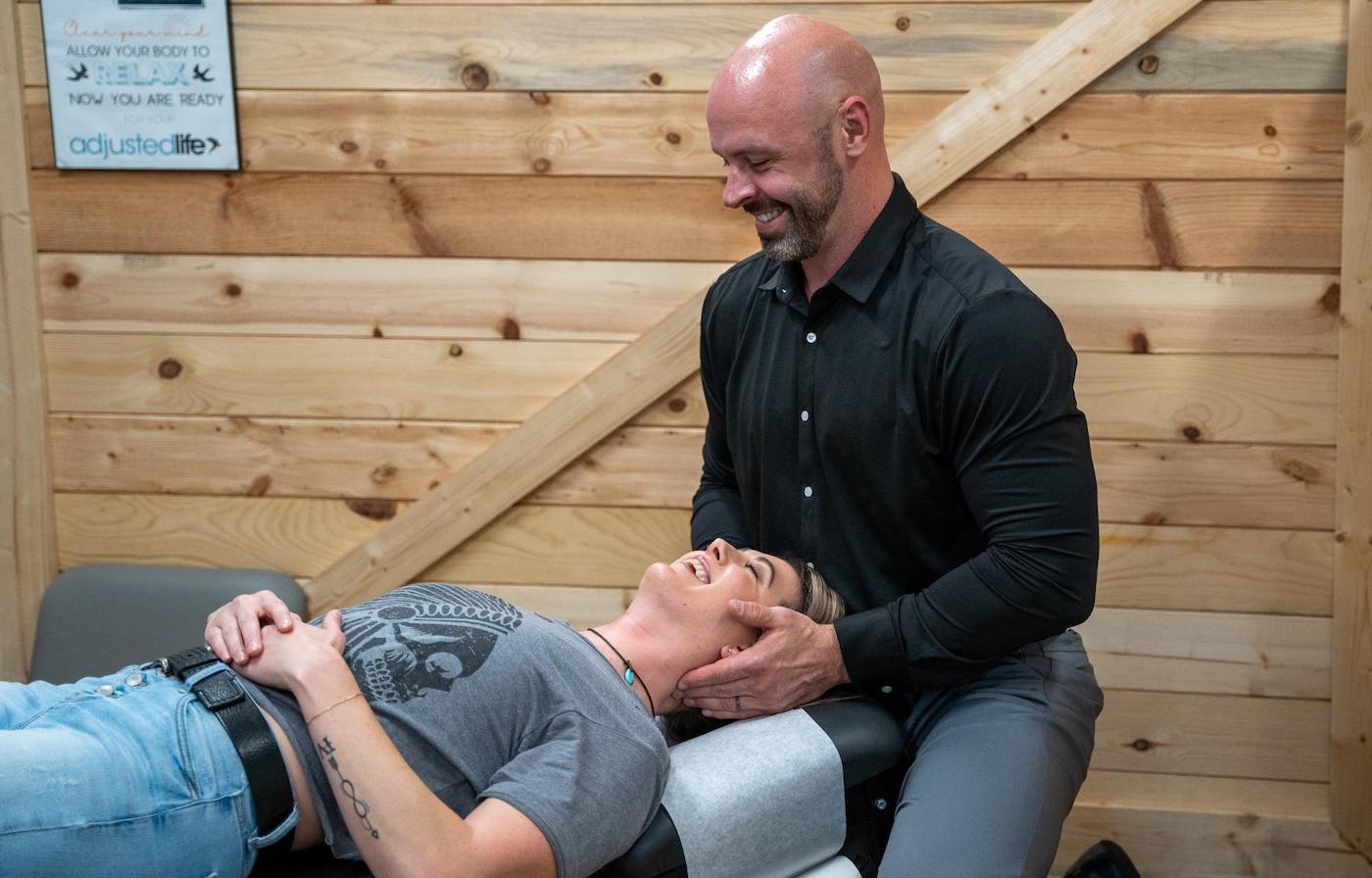 Dr. Coty Spraggs treating a woman's whiplash injury pain with chiropractic adjustment