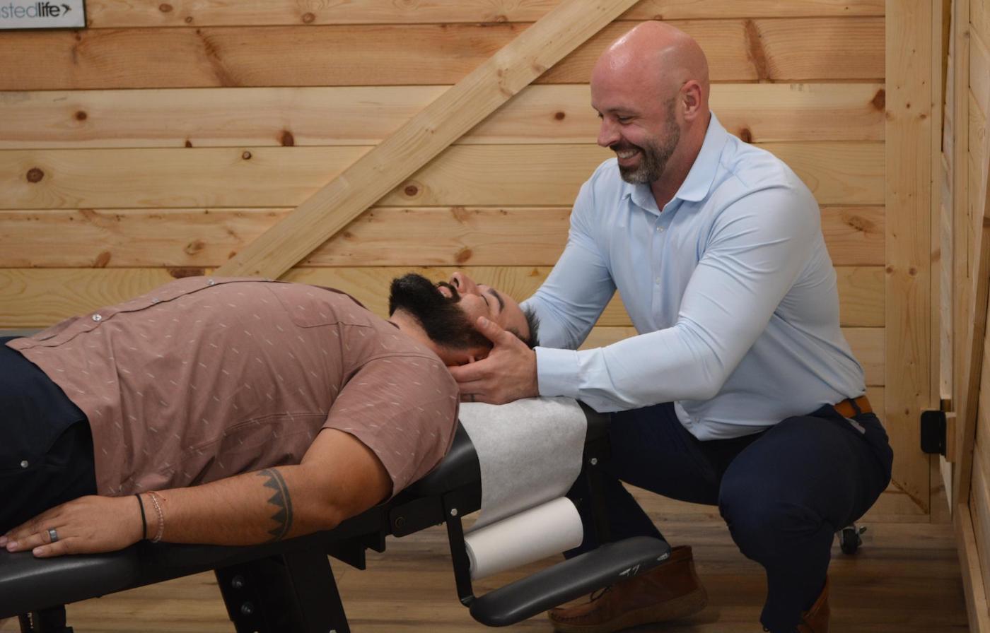 Dr. Coty Spraggs treating a man's migraine pain  with a chiropractic adjustment