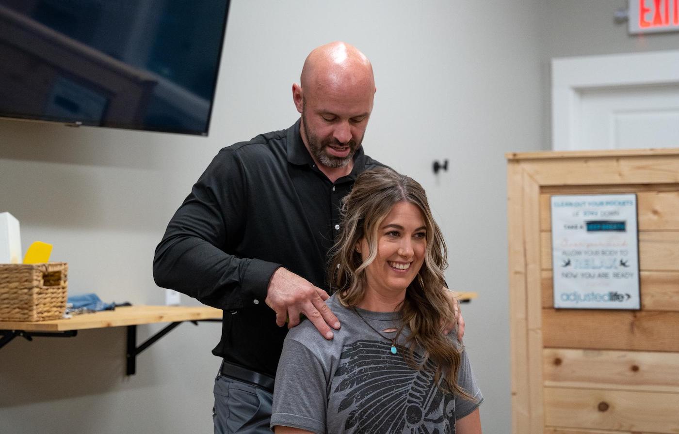 Dr. Coty Spraggs treating a young woman's shoulder pain with a chiropractic adjustment