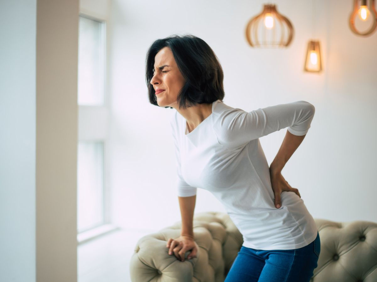 spinal rehab for woman holding her back in pain